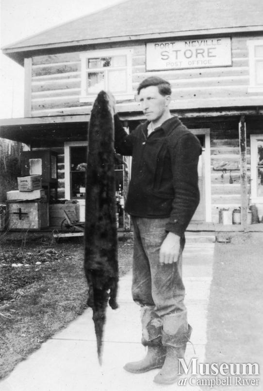 Olaf Hansen with a mink outside the store and post office at Port Neville