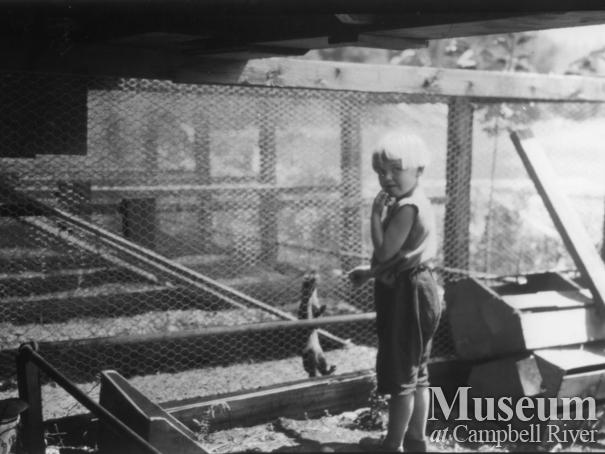 August Schnarr's daughter beside one of his animal cages, 1920s